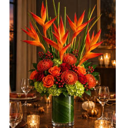 Tall tropical floral arrangement in a glass vase with orange and red blooms