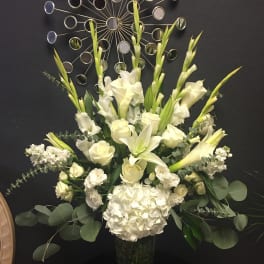 White floral arrangement in a glass vase with tall blooms and greenery