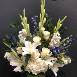 White lilies, cream roses, and blue flowers arranged in a vase