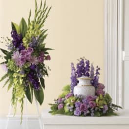 Purple and green floral arrangements with a white urn centerpiece