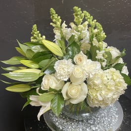 White roses and lilies arranged in a clear glass vase