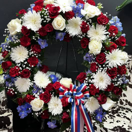Circular wreath of red, white, and blue flowers on a stand