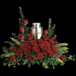 Red roses arranged around a silver urn with greenery