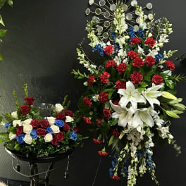 Two floral arrangements with red, white, and blue flowers on black stands.