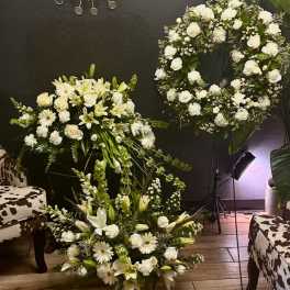White floral wreath and two matching arrangements with lilies and roses