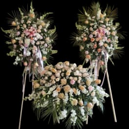 Three large floral standing sprays with pink and peach roses on easels