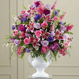 Large mixed bouquet of pink, purple, and white flowers in a white vase