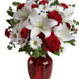 Red roses and white lilies in a red glass vase