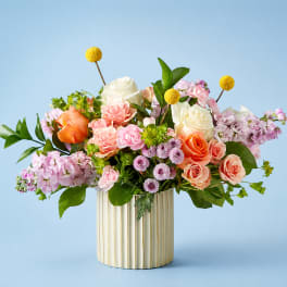 Mixed bouquet of roses and pink flowers in a ribbed cream vase