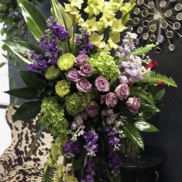 Tall floral arrangement with yellow gladiolus, purple flowers, and pink roses