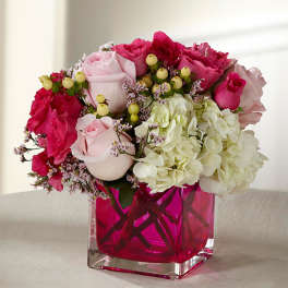 Pink and white rose bouquet with hydrangeas in a magenta glass vase