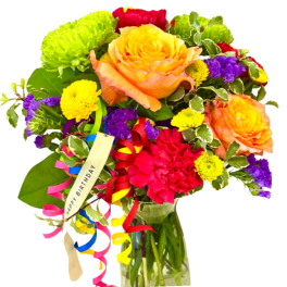 Colorful bouquet with roses, mums, and ribbon in a glass vase