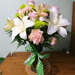 Bouquet of white lilies, pink roses, and carnations in a glass vase