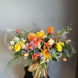 Colorful mixed bouquet in a glass vase with a gold ribbon