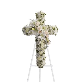 White floral cross on a stand with lilies and roses