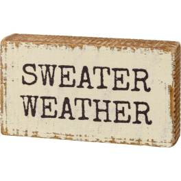 Distressed wooden block sign reading "Sweater Weather"