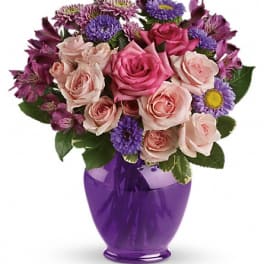 Pink roses and purple flowers arranged in a purple vase