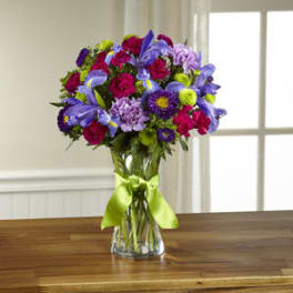 Colorful bouquet in a clear glass vase with a green ribbon
