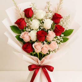 Bouquet of red, white, and pink roses wrapped in pale paper with a red ribbon