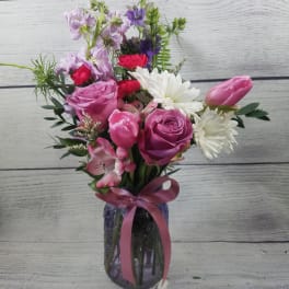 Pink and white mixed bouquet in a glass vase with a ribbon