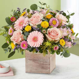 Pink roses and daisies arranged in a wooden box