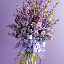 Tall lavender and pink floral arrangement with a large ribbon bow