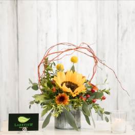 Sunflower arrangement in a metal container with berries and twig accents