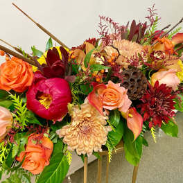 Colorful floral arrangement with roses, chrysanthemums, and calla lilies in a low container