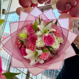 Pink and white bouquet with roses, lilies, carnations, and daisies in pink wrap
