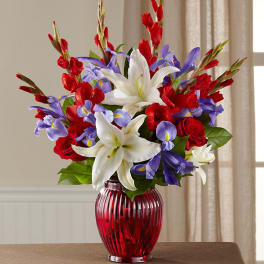 Red, white, and purple floral arrangement in a red glass vase