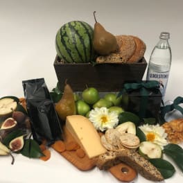 Fruit and cheese gift basket with bread, crackers, flowers, and a bottle of water