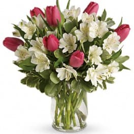 Pink tulips and white flowers in a clear glass vase