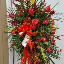 Tall standing floral spray with red roses and orange berries on an easel