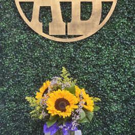 Sunflower bouquet in a clear vase beneath a gold monogram sign