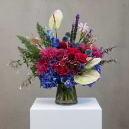 Colorful mixed bouquet in a glass vase with roses, hydrangeas, and anthuriums