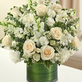 Cream roses and white flowers arranged in a green vase