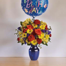 Birthday balloon above a colorful flower arrangement in a blue vase