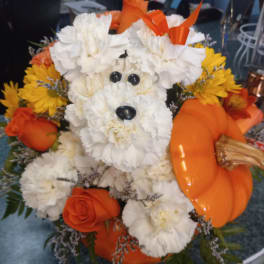 White flower dog arrangement with orange roses and yellow daisies