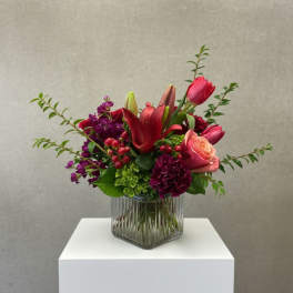 Mixed bouquet of red and pink flowers in a clear glass vase