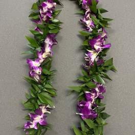 Purple orchid lei with green leaves laid on a gray surface
