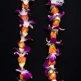 A floral lei made of orange, purple, and white blossoms on a black background