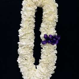 White floral lei with a purple ribbon on a black background