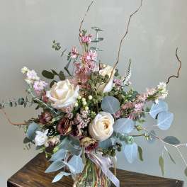 Tall bouquet of cream roses and pink flowers in a glass vase