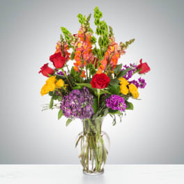 Mixed bouquet of roses, snapdragons, and hydrangeas in a clear glass vase