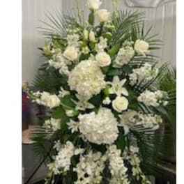 Tall white funeral spray with roses, hydrangeas, and lilies