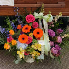 Colorful mixed flower arrangement with roses, gerberas, and orchids in a basket