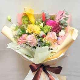 Mixed bouquet with pink and yellow flowers wrapped in cream paper
