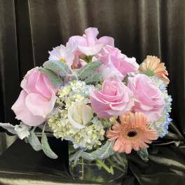 Pink roses and mixed blooms arranged in a clear glass vase