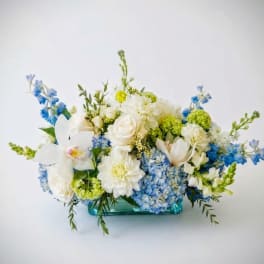 Blue and white floral arrangement in a turquoise glass vase