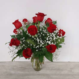 Arrangement of red roses with white filler flowers in a clear glass vase